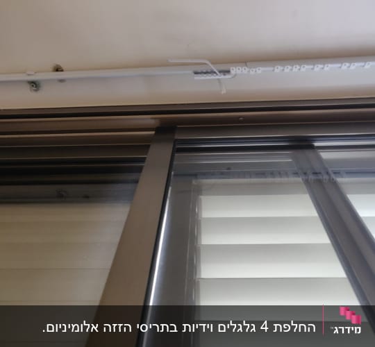 תריסים לבנים עם מסגרת מתכתית בחלון